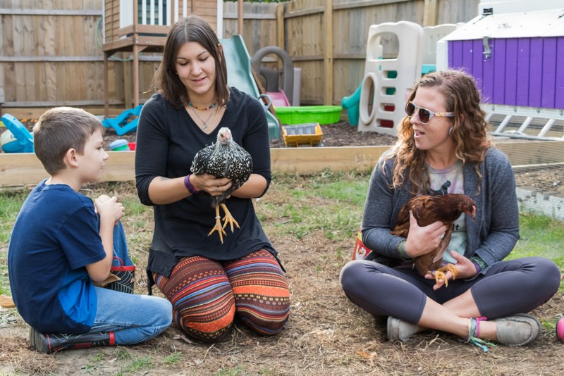 Liz Smith (center), her eight-year-old son Remy, and Mary Petersen with two of Smith’s chickens in Moline.