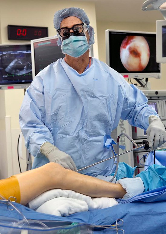Drew Starenko during an endoscopic-vein-harvesting procedure on October 28. Through a two-centimeter incision, Starenko removed more than a foot of saphenous vein for use in a heart bypass. The monitor over his left shoulder was one of several in the operating room showing the view from the endoscopic camera. Photo provided by Genesis Health System.