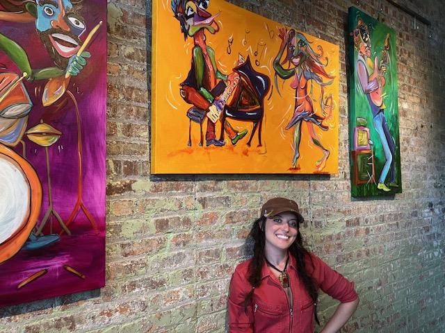 Miranda Vavrosky with some of her musician paintings at Art on the Bend, Thursday, September 5, 2024 (photo by Jonathan Turner)